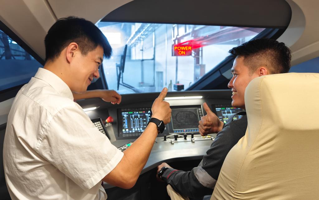 8月25日，在印度尼西亞萬隆的雅萬高鐵德卡魯爾動車所內，中國師傅穆振（左）在向印尼火車司機塞蒂亞萬講解動車組出庫前的上電作業。