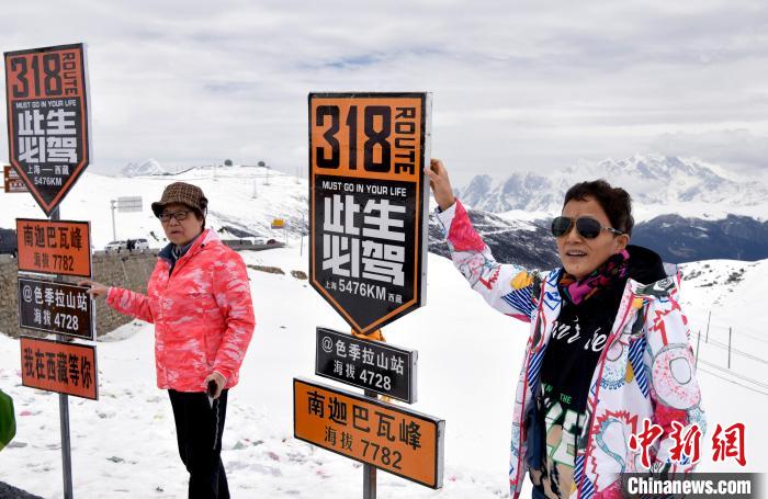 圖為5月14日，西藏林芝色季拉山觀景臺(tái)，游客與南迦巴瓦峰合影。　李林 攝